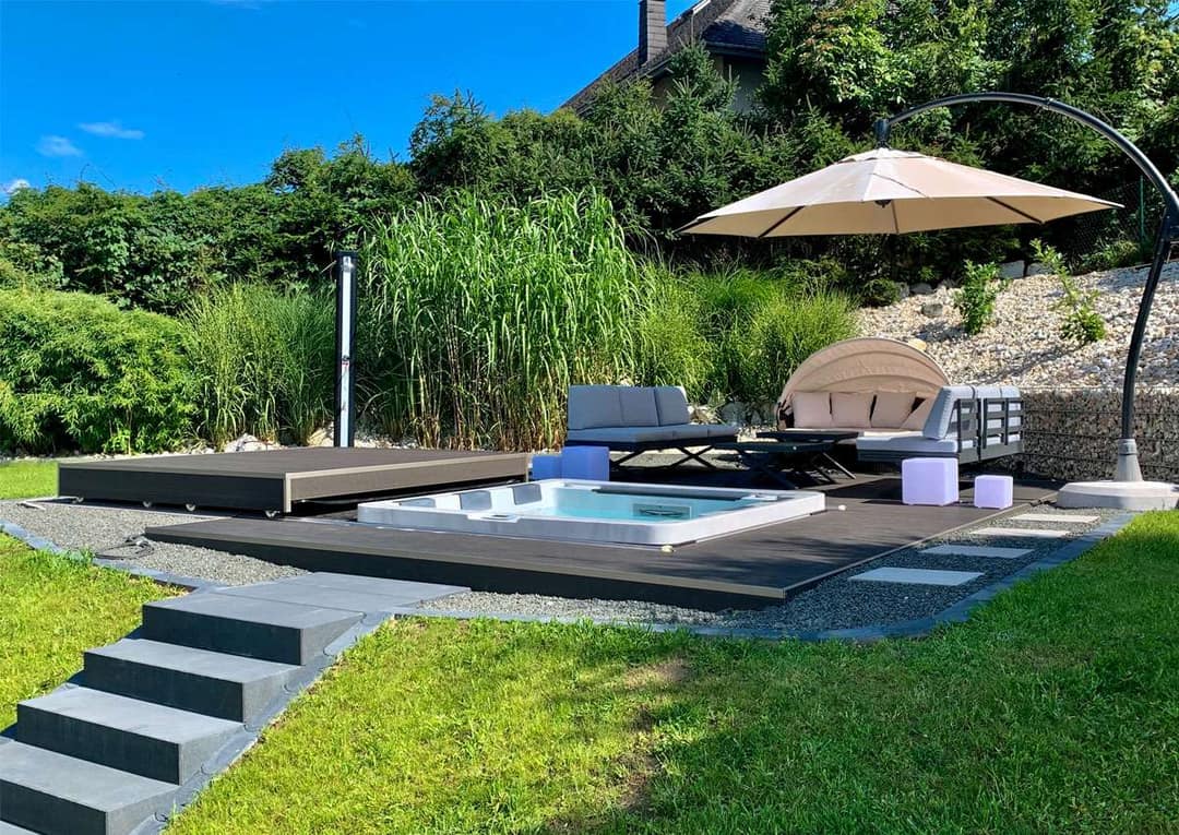 In eine Holzterrasse eingelassener Whirlpool in einem Garten